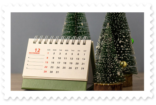 A colorful photograph of a desktop calendar displaying the month of December and three small decorative Christmas trees.