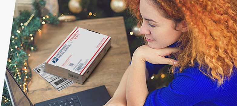 Woman on laptop with Priority Mail box and printed shipping label on the table next to her.