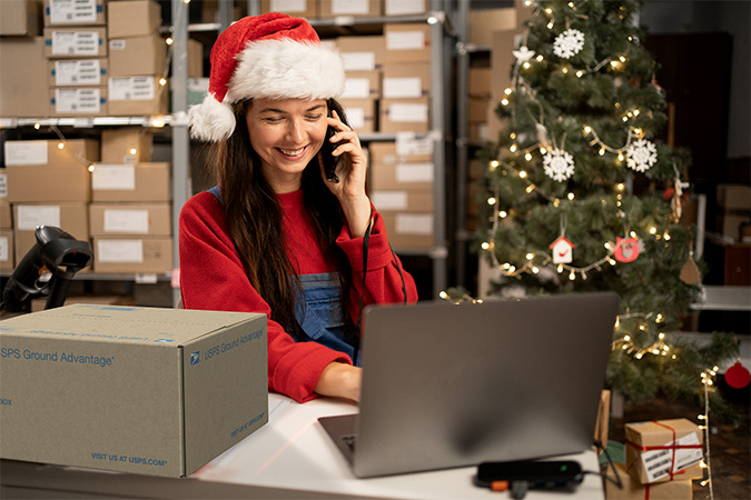 A business owner dressed up in festive holiday attire preparing to ship a USPS Ground Advantage box.