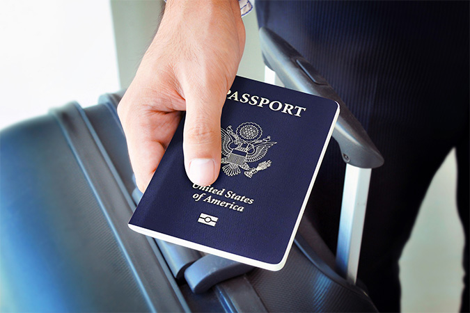 A passport being held above luggage.