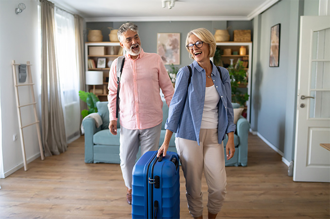 Two people with luggage happily standing in a room.