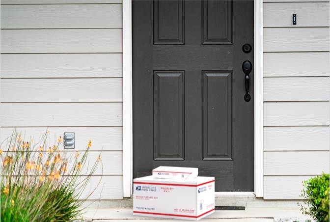 Priority Mail boxes on a house porch awaiting pickup.