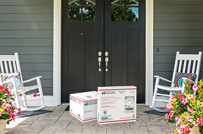 Priority Mail boxes on a house porch awaiting pickup.